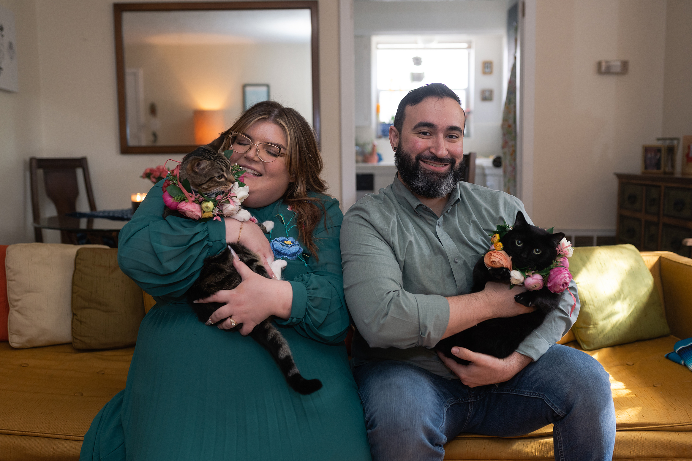 couple smiles with their two cats wearing flower collars during their engagement session in Houston Texas by Swish and Click Photography