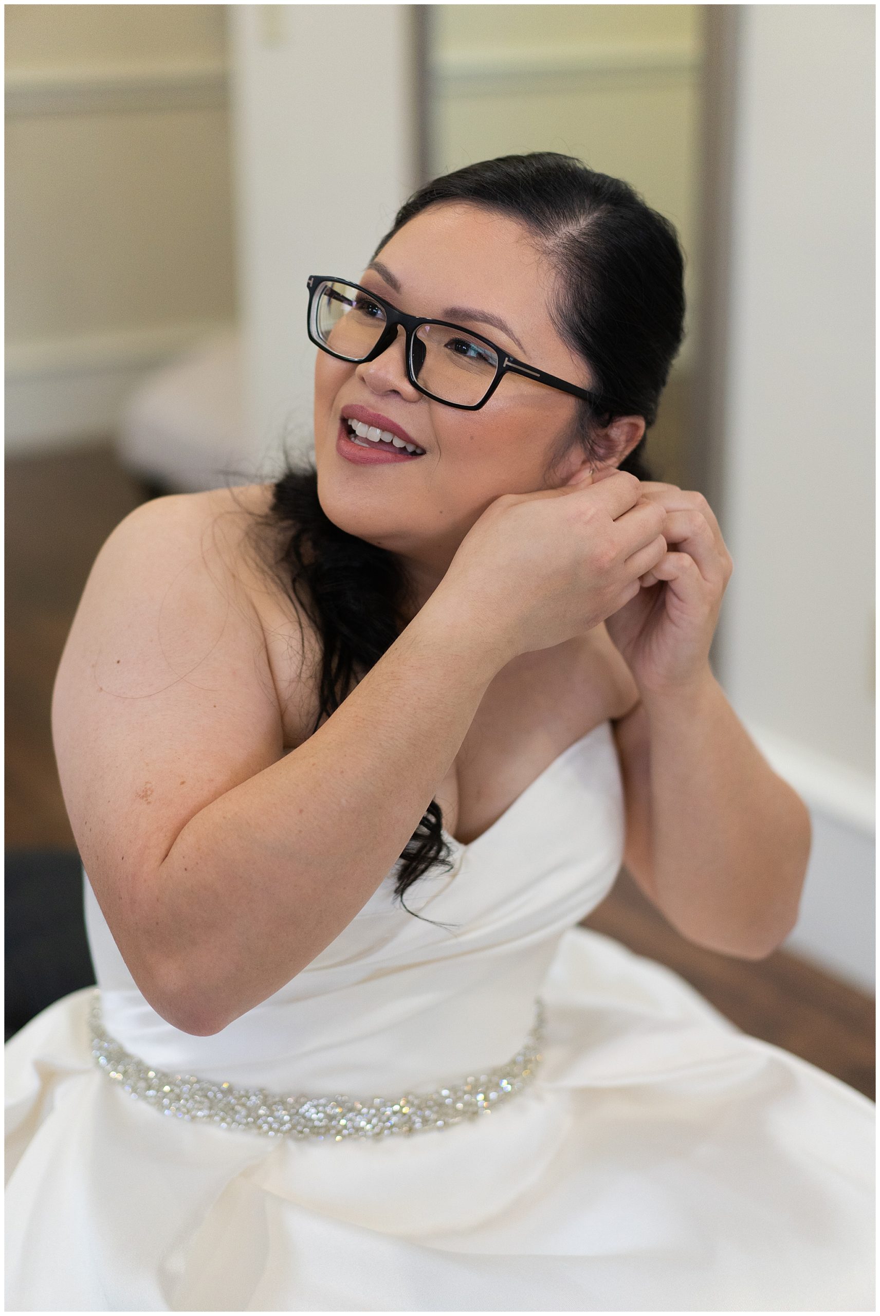 bride puts on earring at Ashton Gardens in Houston Texas by Swish and Click Photography