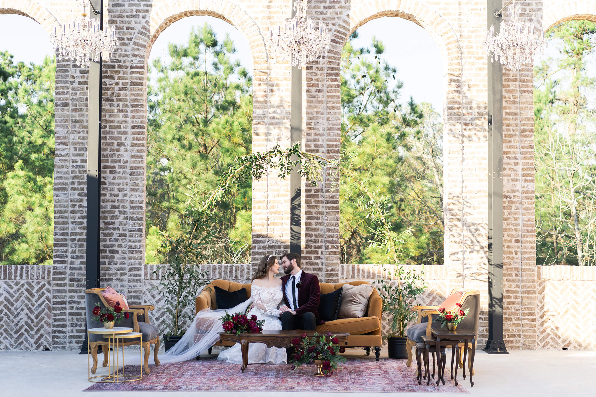 bride and groom kiss while sitting on a couch in the courtyard bride looks at herself as she gets ready on her wedding day reception space at Iron Manor in Houston Texas by Swish and Click Photography