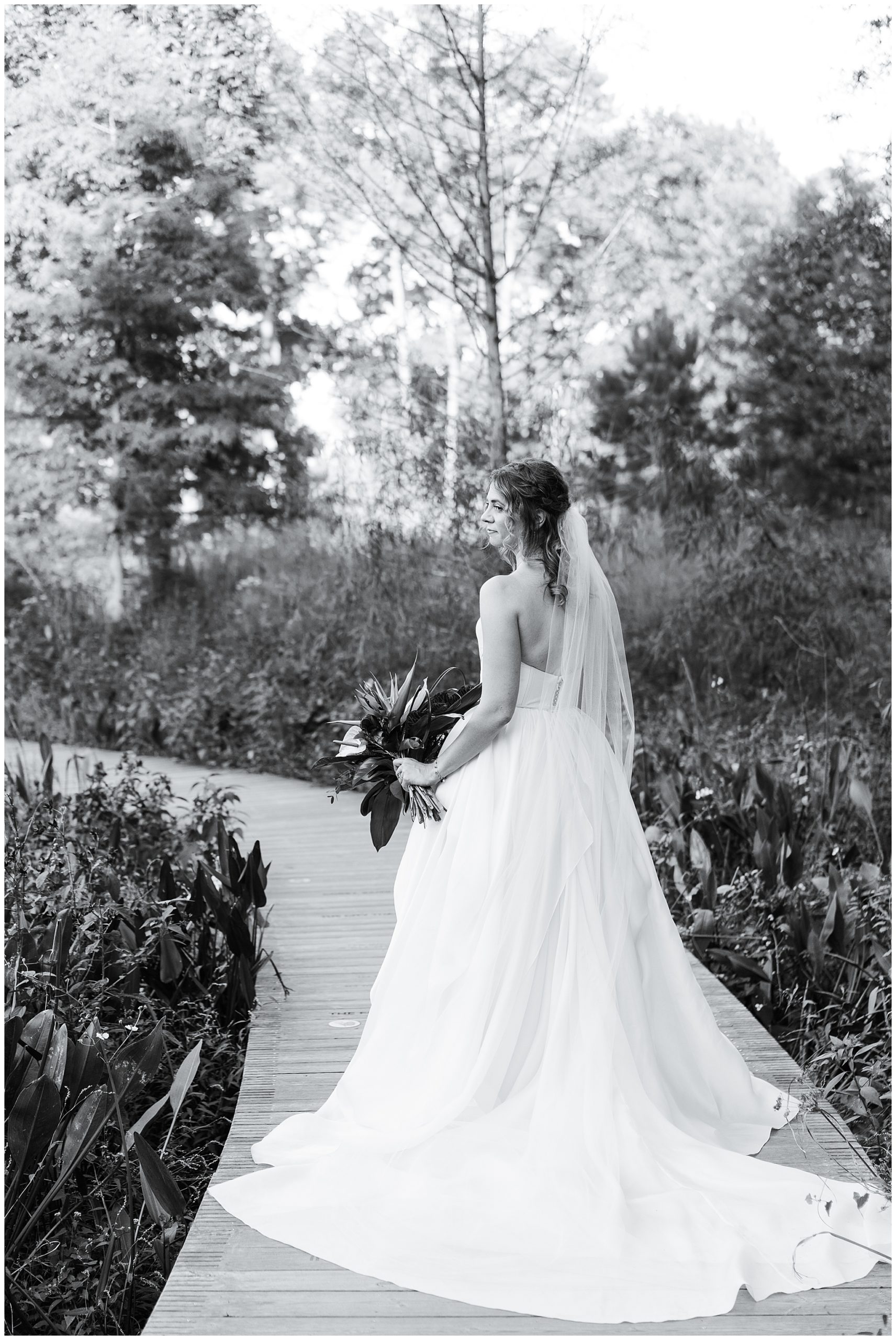 bride poses by the water during her bridal portraits at the Houston Arboretum by Swish and Click Photography