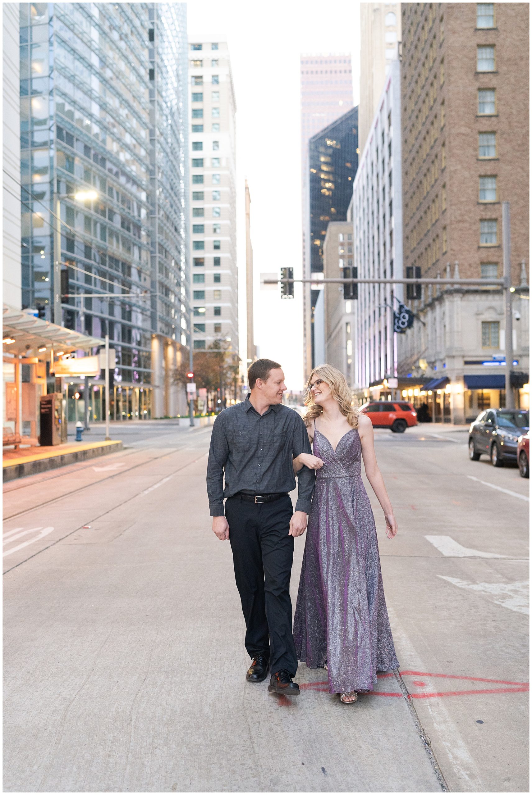 engaged couple walk in the middle of the street in downtown Houston during their engagement session by Houston's best wedding photographers Swish and Click Photography