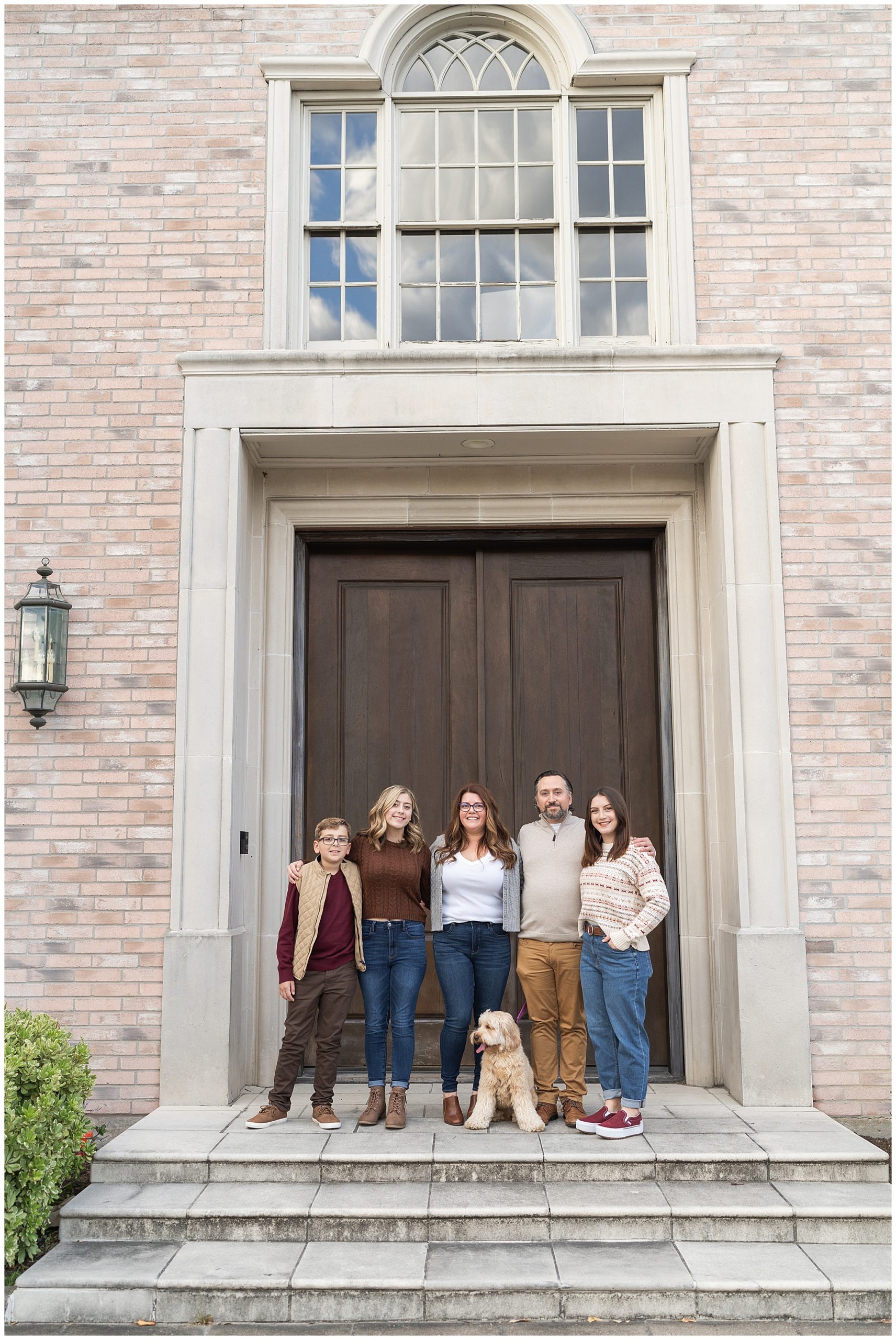 family stand in the doorway with their dog for photos at the Creative Chateau in Houston Texas by photographer Swish and Click Photography