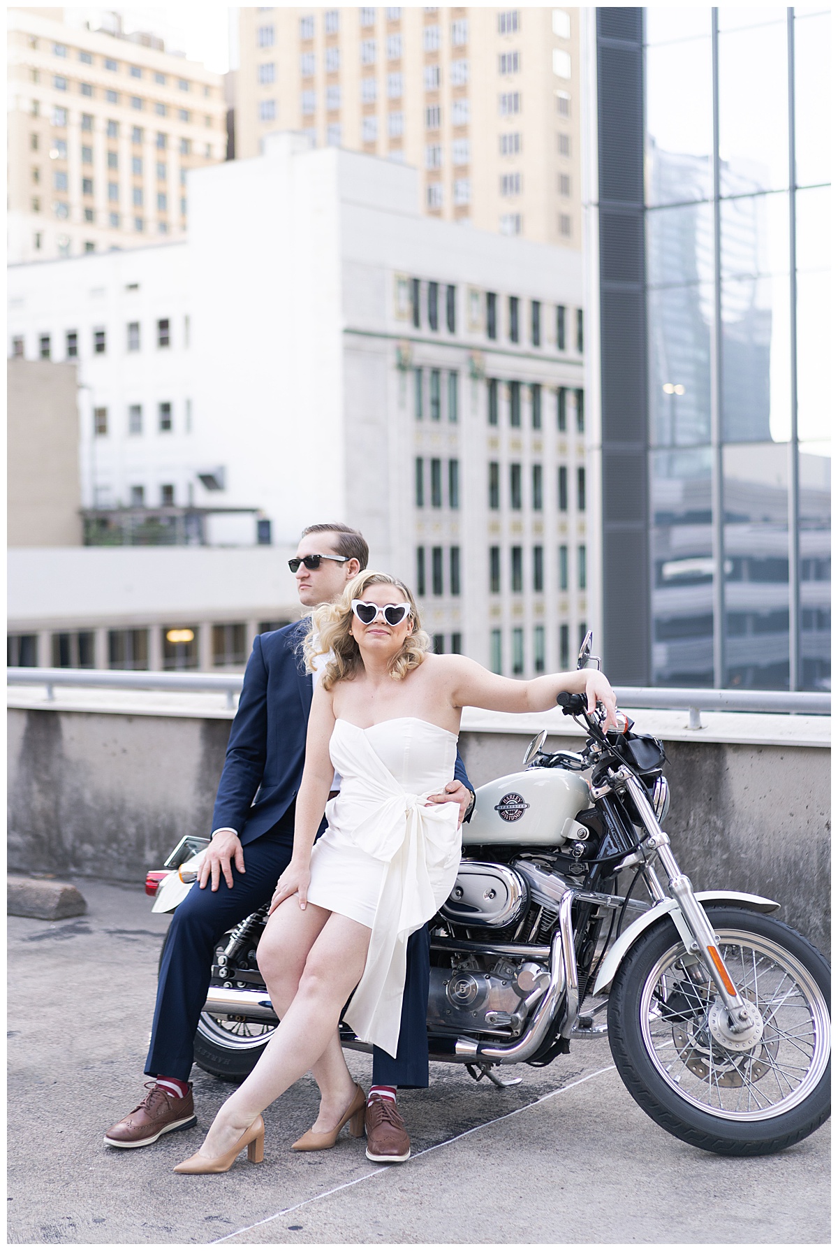 Two adults sit on edge of motorcycle on rooftop for Houston’s Best Wedding Photographers