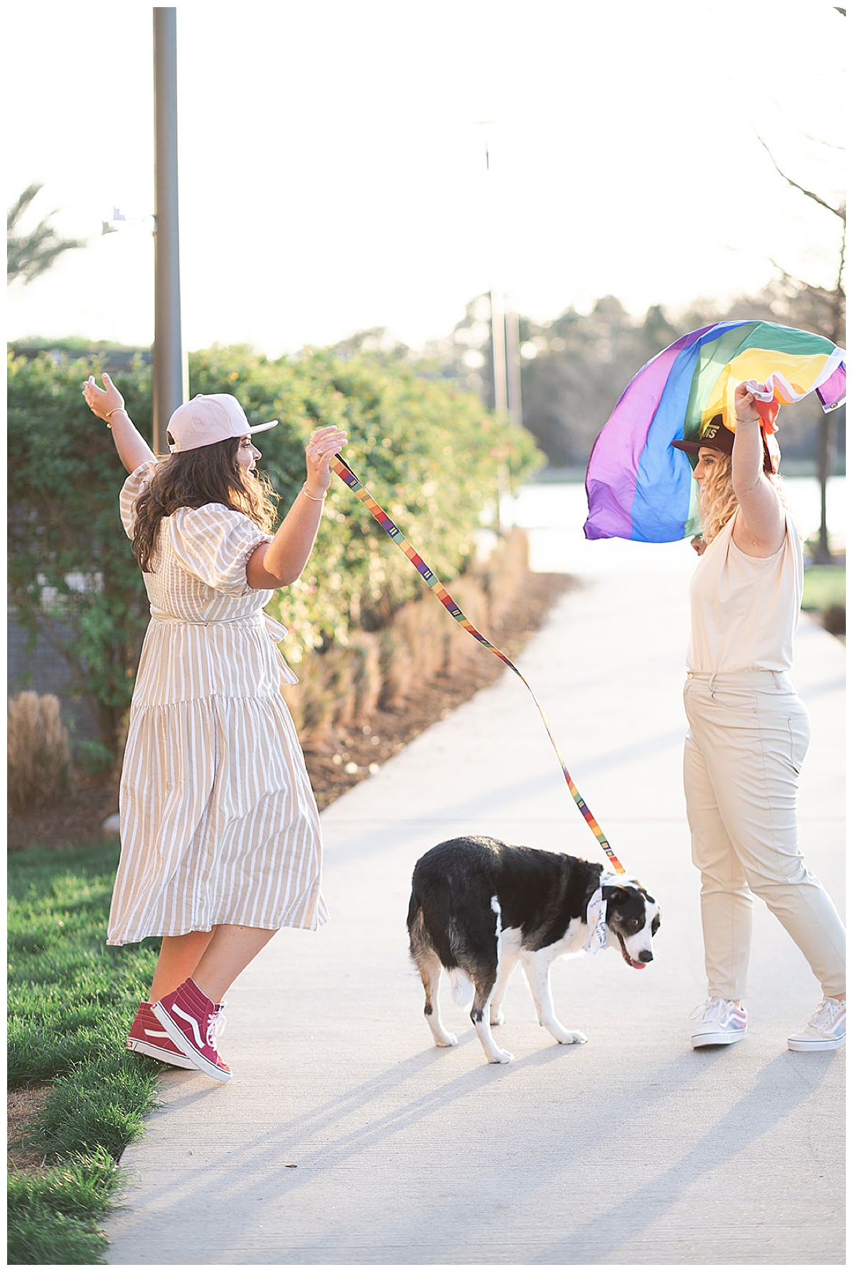 Women dance together with their dog holding a Pride flag after WG Jones Park Engagement Session 