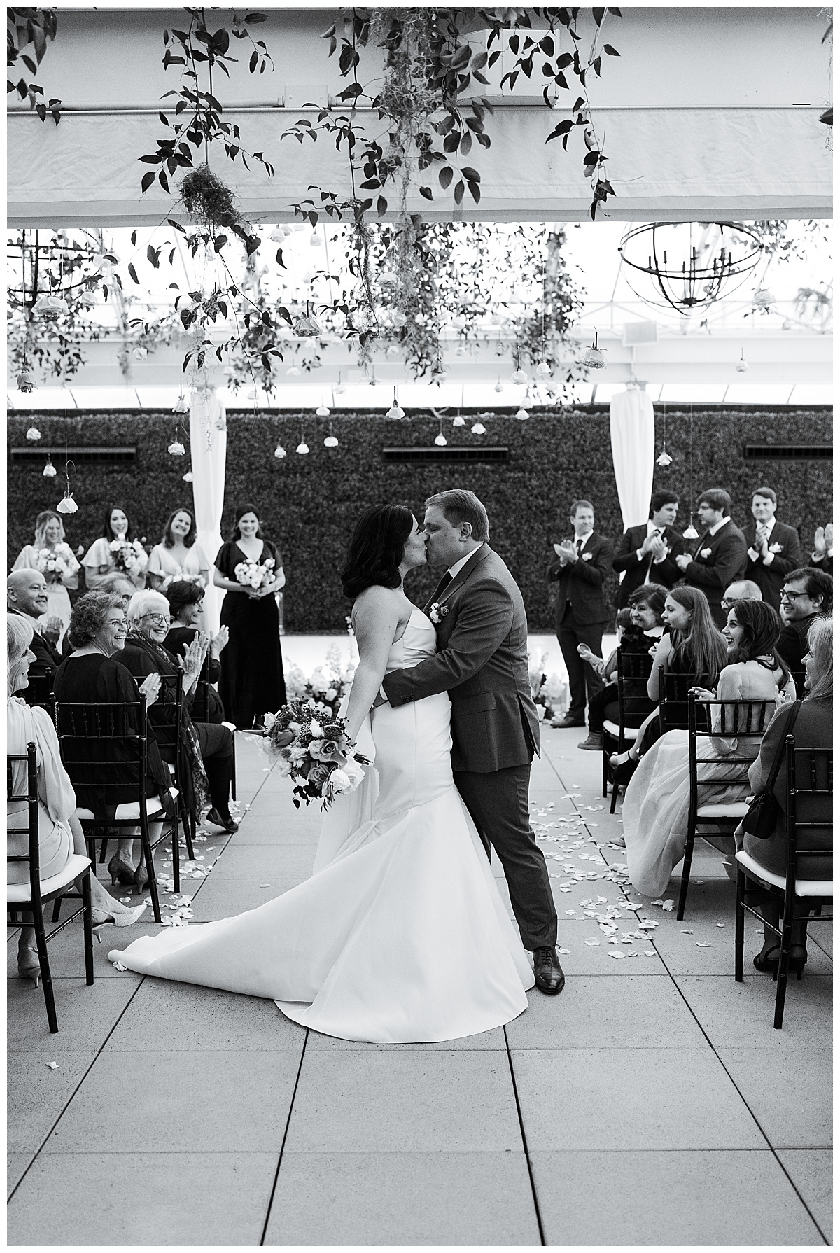 Couple kiss at the end of the aisle at The Sam Houston Hotel
