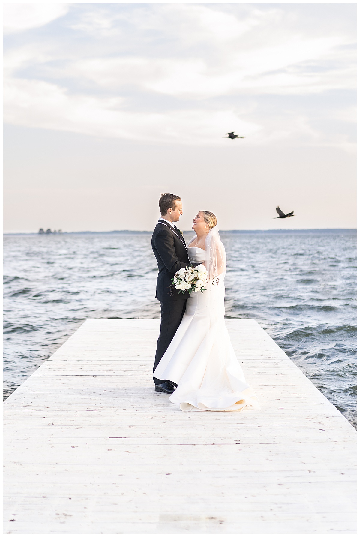 Bride and groom stand on a deck for Swish & Click Photography