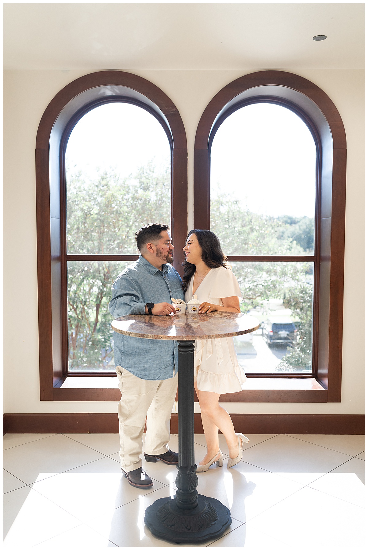 Couple smile in front of the window during Blue Bell Engagement Session