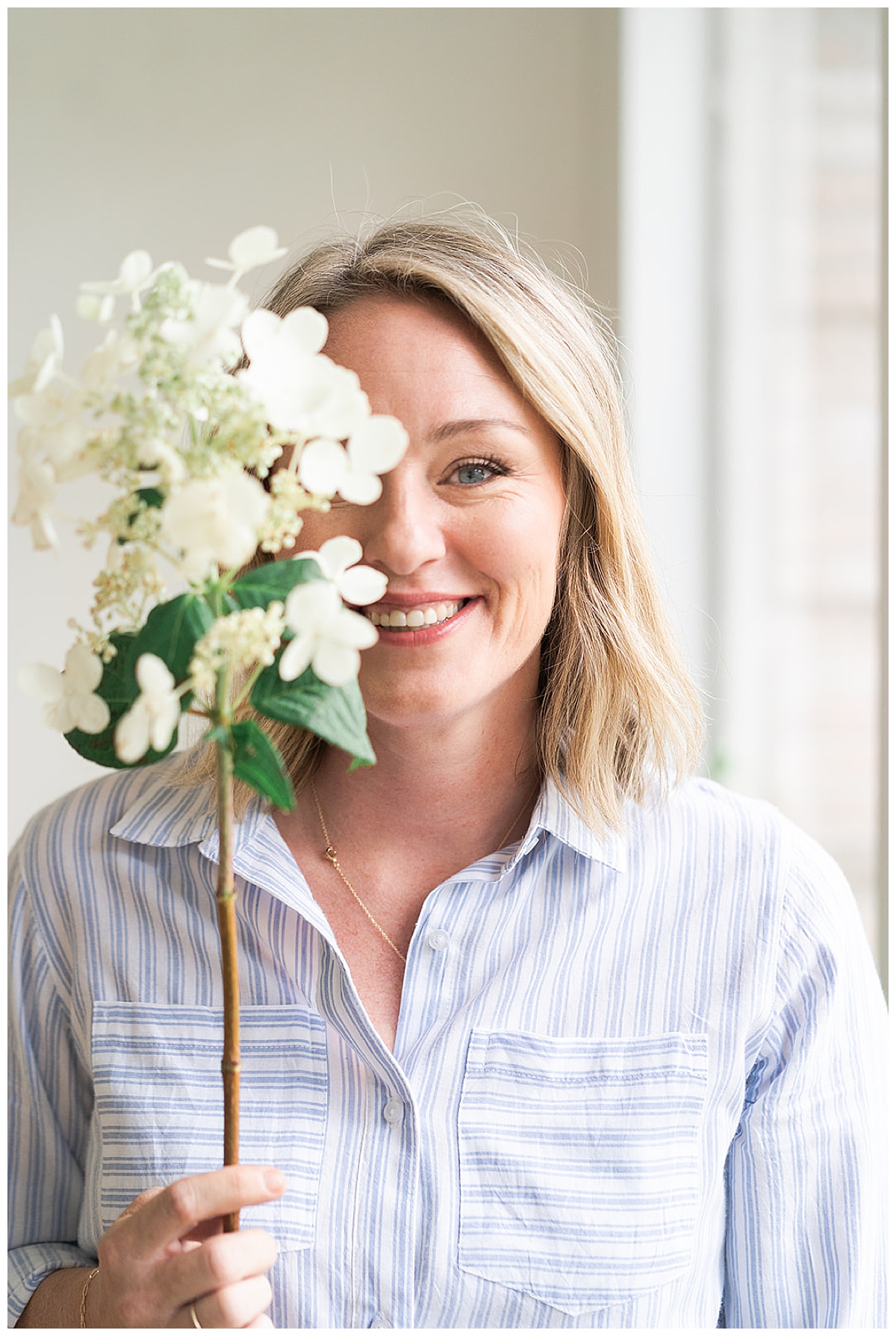 Woman smiles behind a flower during a Branding Session for College Park Flowers