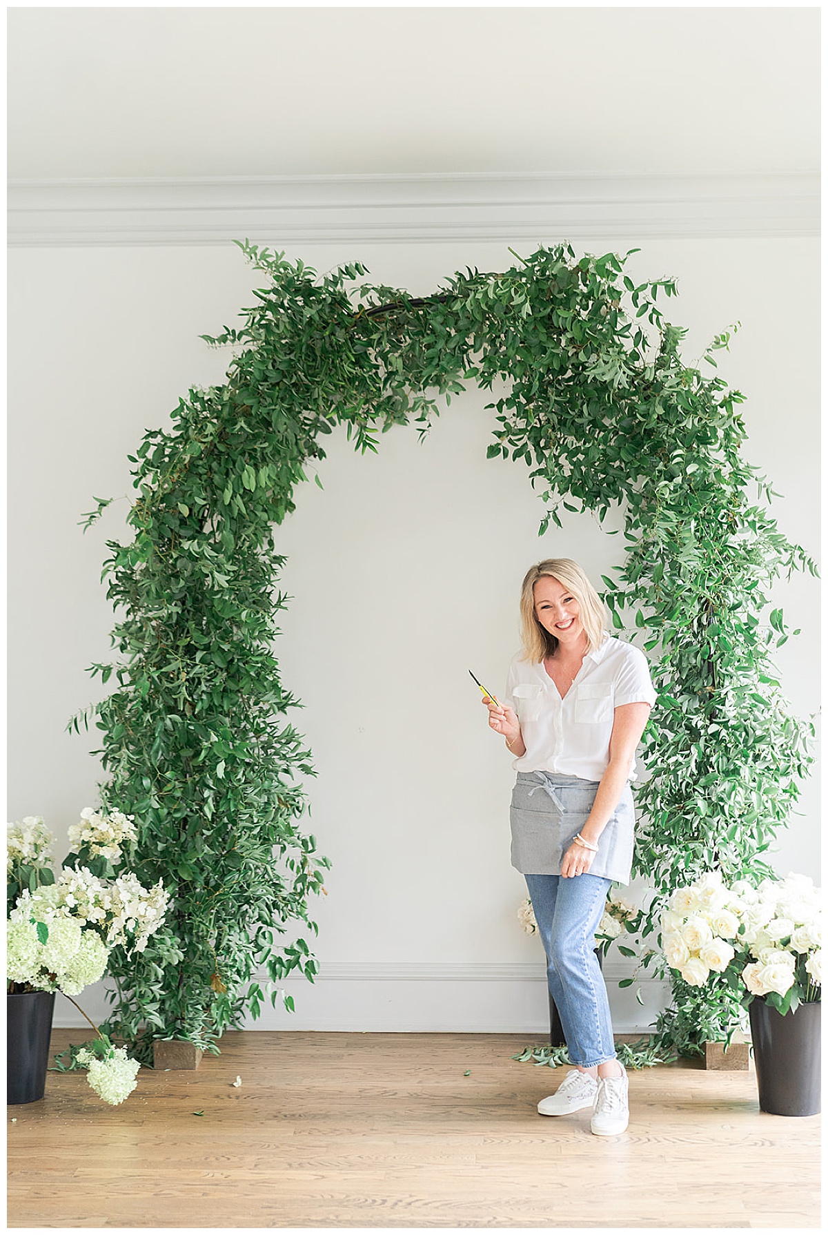 Woman stands in front of floral arch during a Branding Session for College Park Flowers