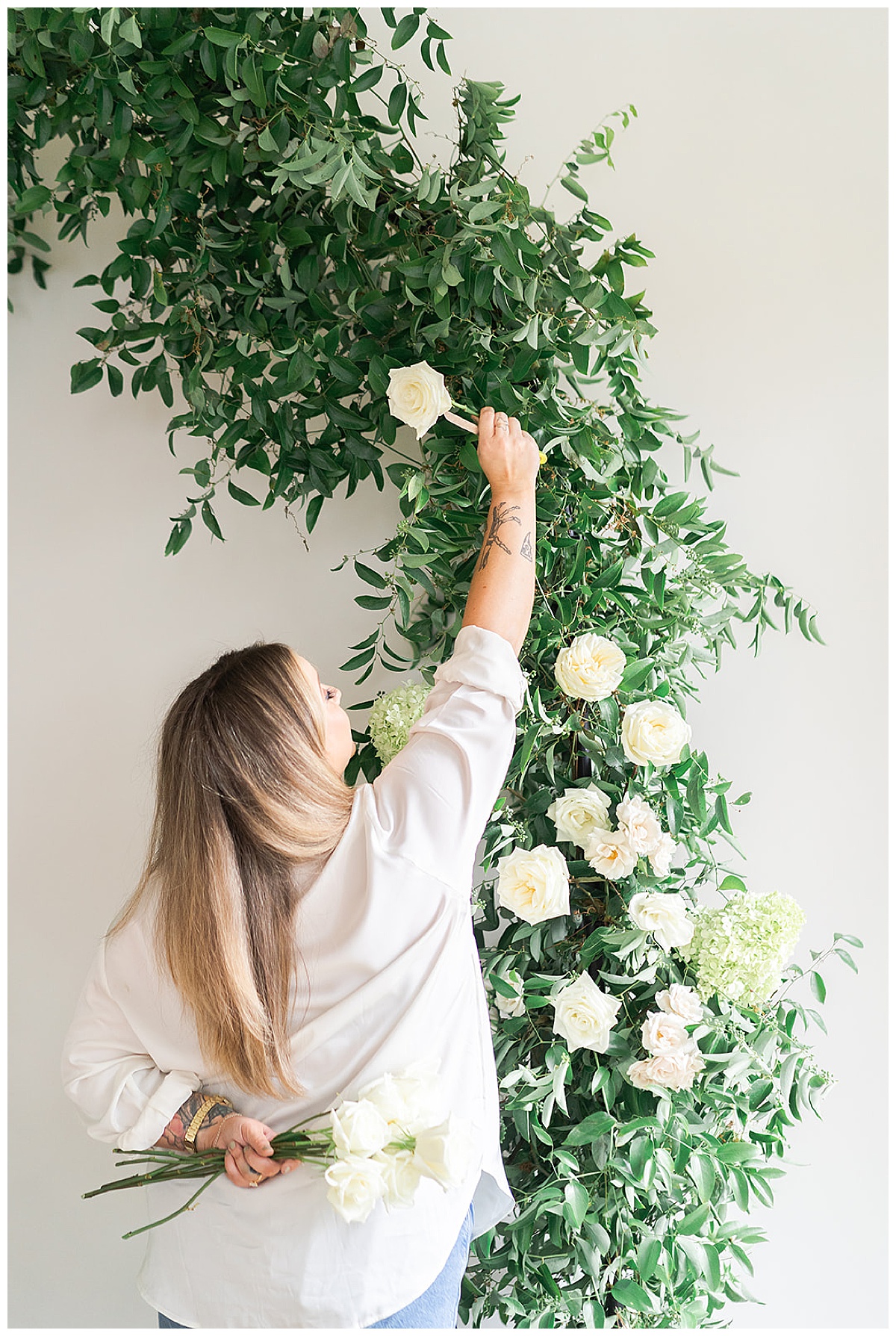 Woman installs a flower into an arch for Swish & Click Photography
