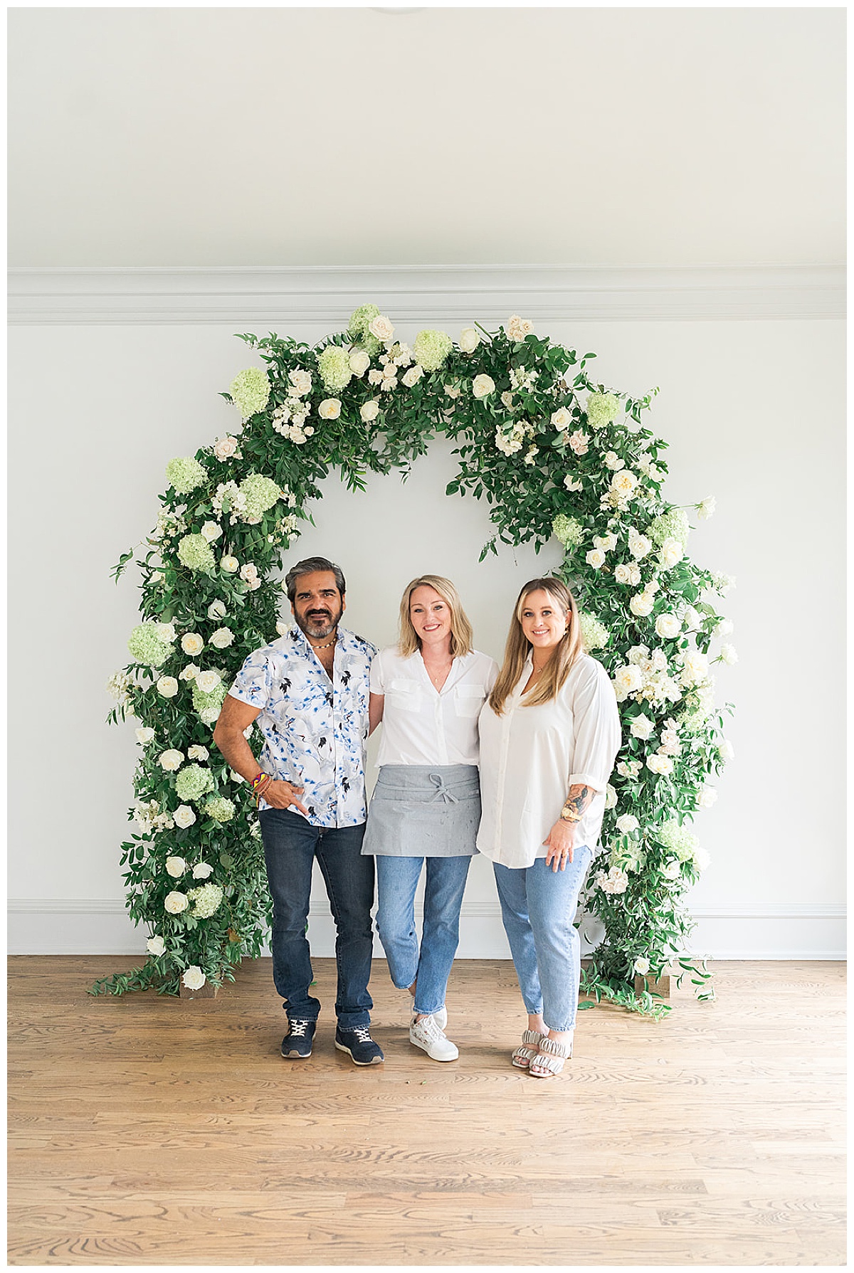 Three people stand in front of a floral arch for  Houston’s Best Wedding Photographers