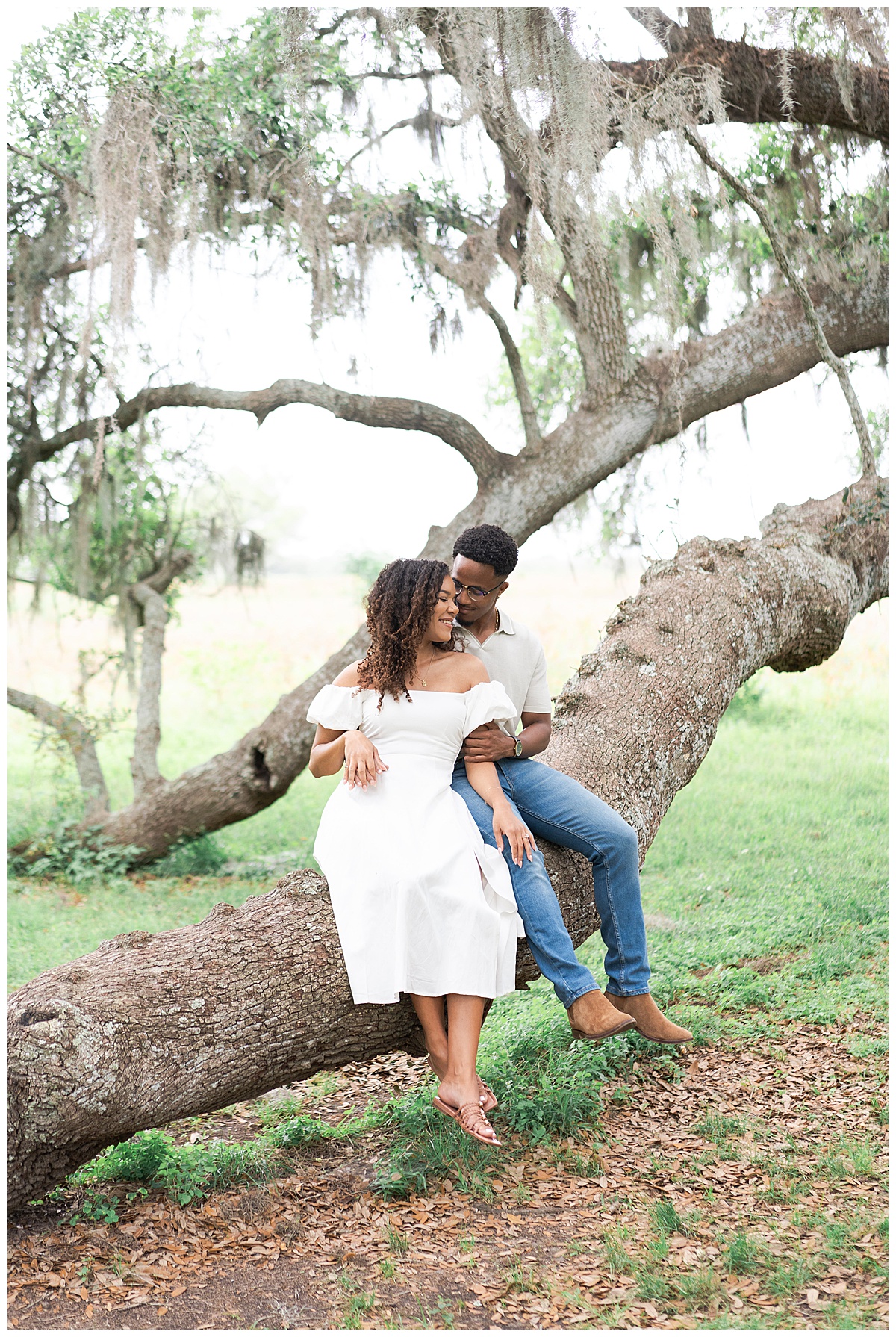 Couple sit together on tree during Brazos Bend Engagement Photographer 