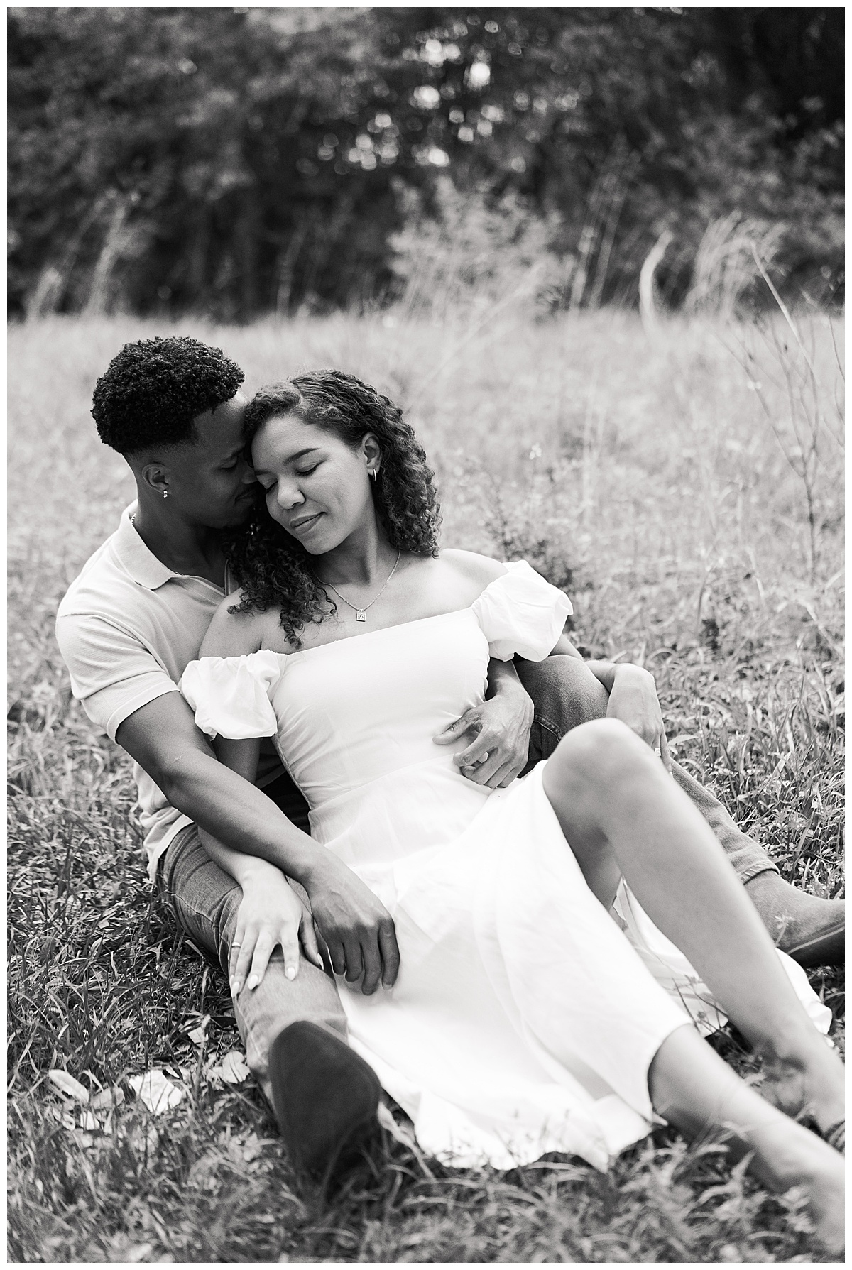 Couple cuddle together in grassy field during their Brazos Bend Engagement Photographer 