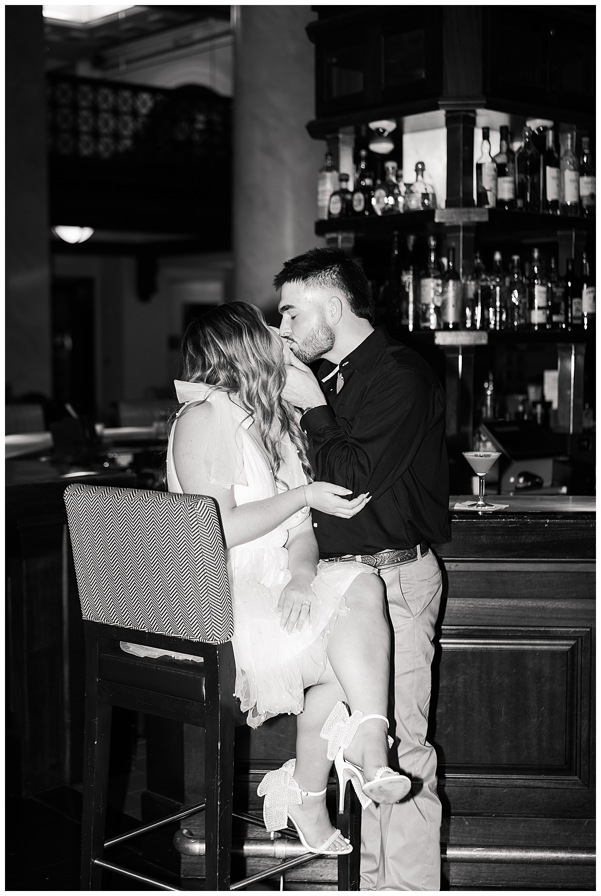 Couple share a kiss in a bar showing one of the Best Engagement Photo Locations in Houston