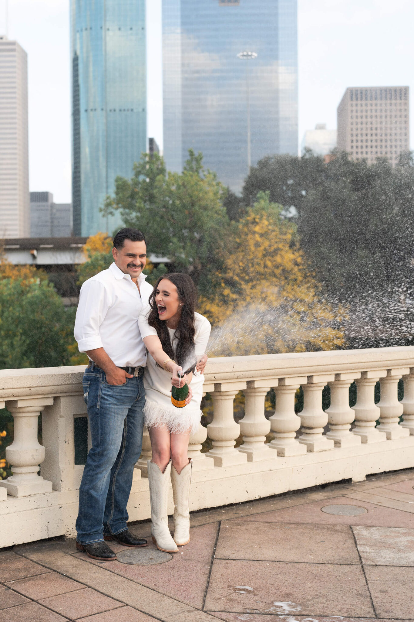 couple sprays champagne on Sabine Street Bridge during their engagement session