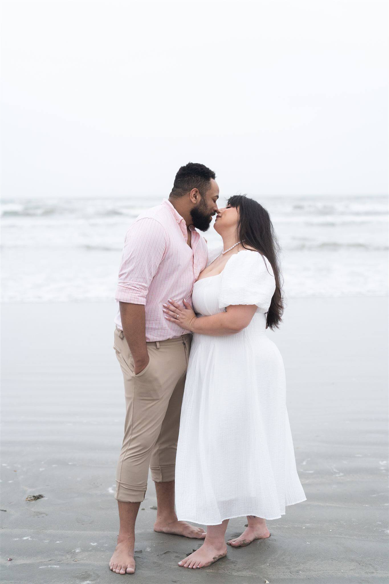 couple embrace during their engagement session at Galveston Beach by Swish and Click Photography