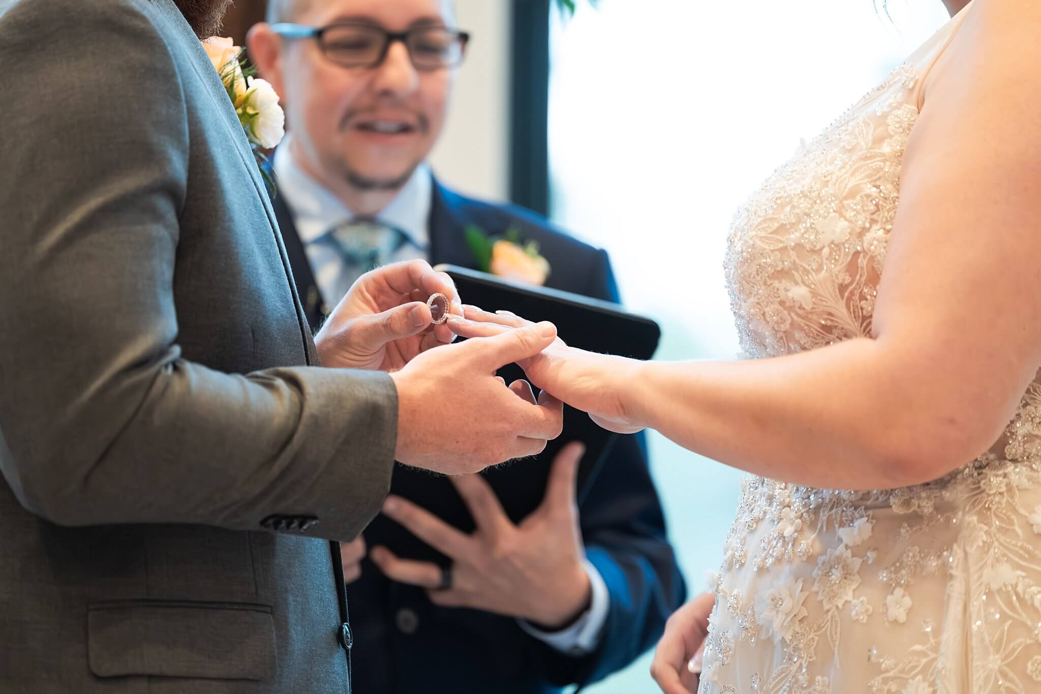 Bride and groom exchange wedding rings on their wedding day captured by wedding photographer Swish and Click at the Blue Magnolia