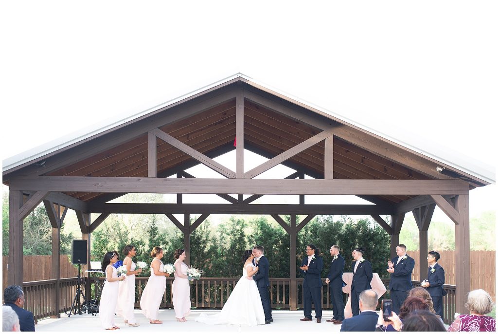 bride and groom first kiss at Bridal Oaks in Cypress Texas by Houston wedding photographer Swish and Click Photography